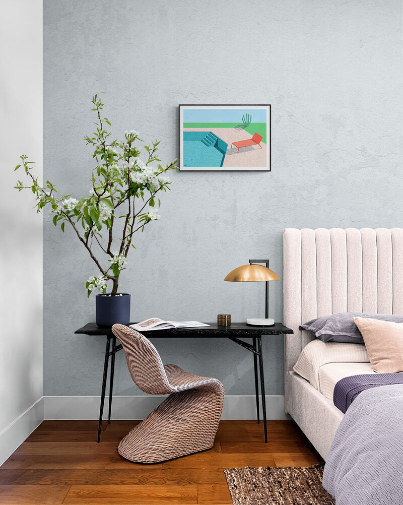 Small landscape print in a bedroom with a black desk and blossom branches