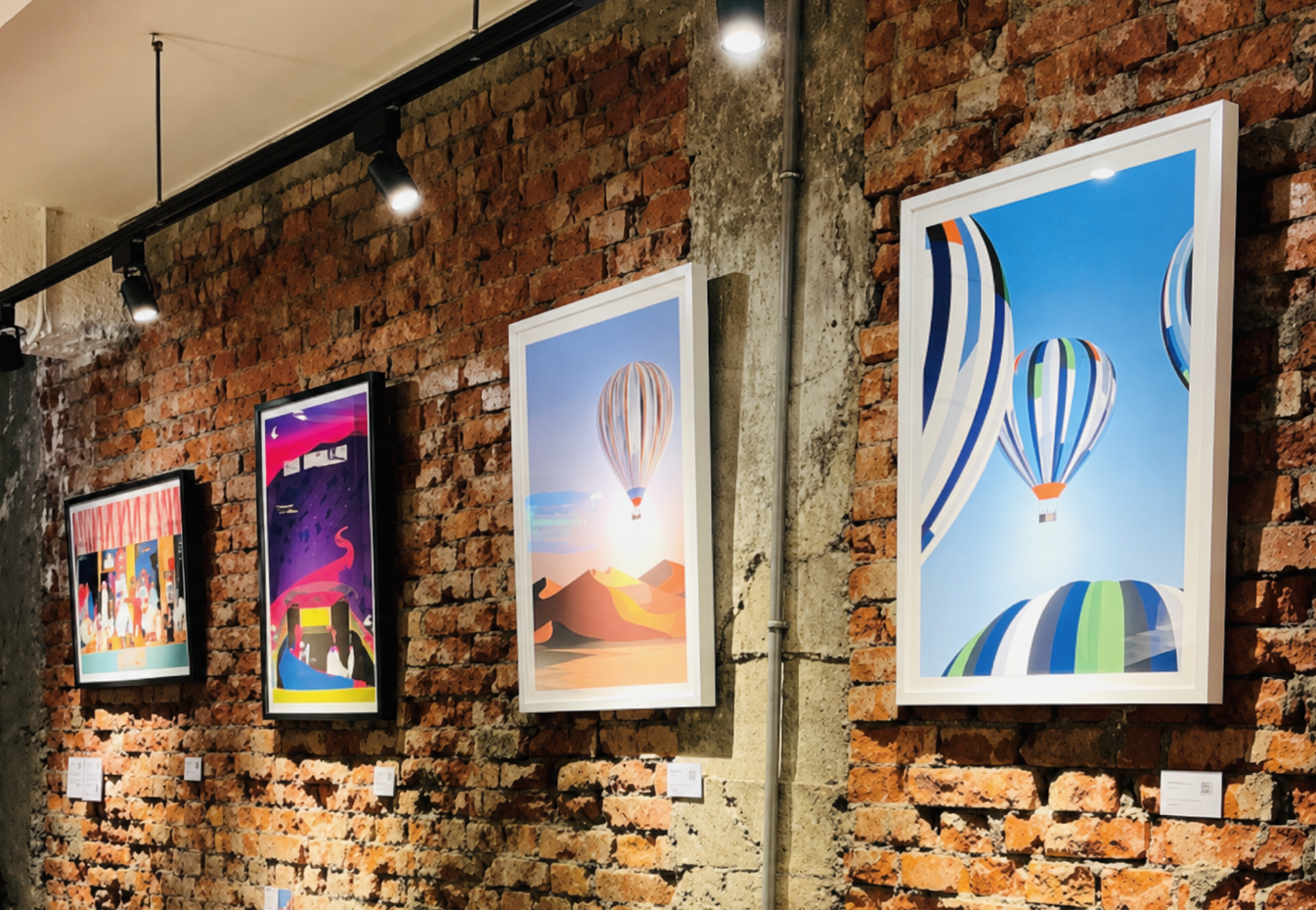Framed art prints displayed on a brick wall at the Heritage Café pop-up in Taipei