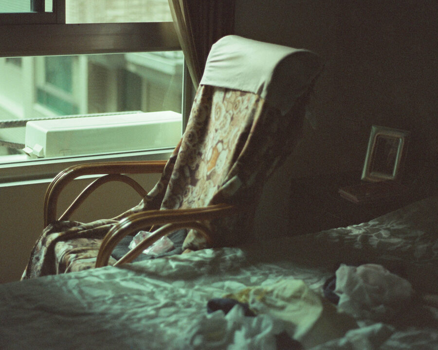 An empty cane rocking chair beside a bright bedroom window